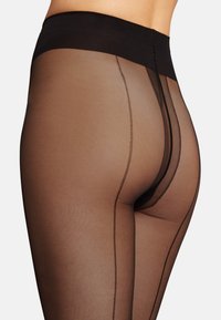 Collant trasparenti marroni con un'alta vita nera, caratterizzati da cuciture verticali nere lungo le gambe per un tocco di dettaglio e texture.