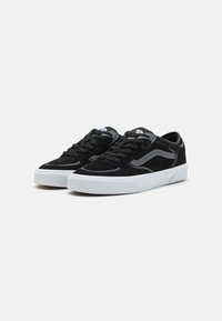 Svarte semskede sneakers med hvit gummisåle, med en kontrasterende grå stripe og svarte lisser. Lavt snitt med polstret krage.