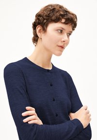 Marineblauer Cardigan mit langen Ärmeln, Rundhalsausschnitt und Knopfverschluss. Weiche Textur mit subtilen Variationen im Stoff.