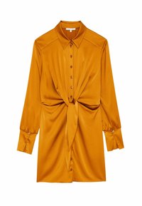 Camicia in satin giallo senape con apertura a bottoni frontale, maniche lunghe e dettaglio in vita annodato. Presenta un colletto e polsini strutturati.