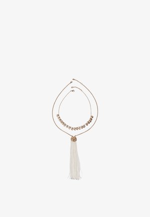 Deux colliers superposés en ton or, l'un avec de petites breloques rondes et l'autre avec un disque texturé et un pendentif à pampille blanche, sur un fond blanc.