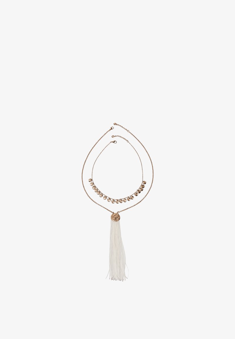 Deux colliers superposés en ton or, l'un avec de petites breloques rondes et l'autre avec un disque texturé et un pendentif à pampille blanche, sur un fond blanc.