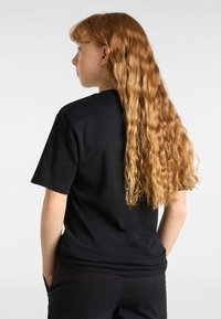 Camiseta negra de manga corta con un ajuste relajado, hecha de algodón. Presenta un diseño limpio y un escote redondo.