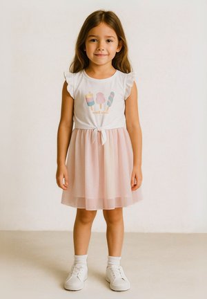 T-shirt en coton blanc avec un motif de glace, manches volantées ; jupe en tulle rose, détail de lien à la taille, portée avec des baskets blanches et des chaussettes.