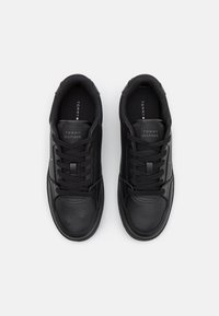 Baskets noires avec une tige en cuir lisse, bout arrondi, fermeture à lacets, semelle en caoutchouc texturée et logo sur la languette.