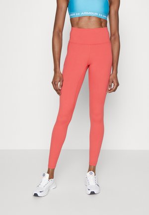 Leggings corallo con vita alta, realizzati in un tessuto elastico e morbido; abbinati a un crop top blu e scarpe sportive bianche.