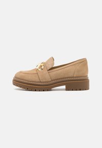 Mocassini in suede beige chiaro con un accento in hardware dorato, caratterizzati da una suola spessa e texturizzata e cuciture rinforzate lungo i bordi.