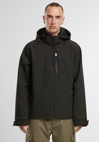 Černá softshellová bunda s kapucí, předním zipem a nastavitelnými šňůrkami; obsahuje velké boční kapsy a má elegantní, minimalistický design.