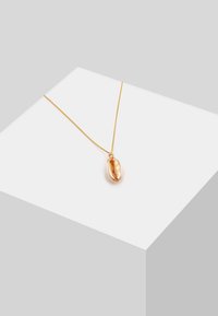 Guldtonet halskæde med en delikat kæde og en poleret cowrie-skal pendant, der har en glat overflade og detaljeret udsmykning.