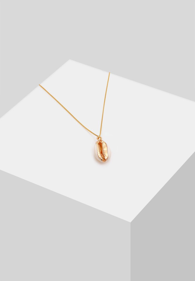 Guldtonet halskæde med en delikat kæde og en poleret cowrie-skal pendant, der har en glat overflade og detaljeret udsmykning.