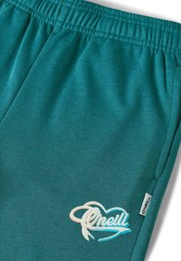 Turkooizen joggingbroek met elastische tailleband, met een wit en lichtblauw O'Neill-logo geborduurd op de linker dij. Glad materiaal.