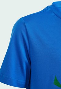 T-shirt blu a maniche corte con una texture liscia, caratterizzato da un accento di design geometrico verde sulla parte anteriore inferiore e un collo a girocollo a costine.