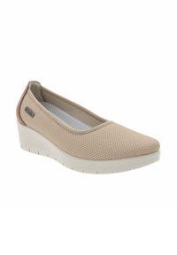 Zapato de color beige tipo slip-on con parte superior de malla texturizada, puntera redondeada y tacón cuña blanco. Incluye forro de malla gris y un sutil detalle de marca.