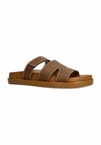 Brown leather slide sandals with two overlapping straps, white stitching accents, and a flat rubber sole. Open toe design.