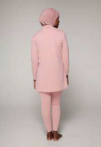 Roze lange tuniek en legging set gemaakt van zachte stof, met een eenvoudig ontwerp, volledige bedekking en een bijpassende hoofddoek.