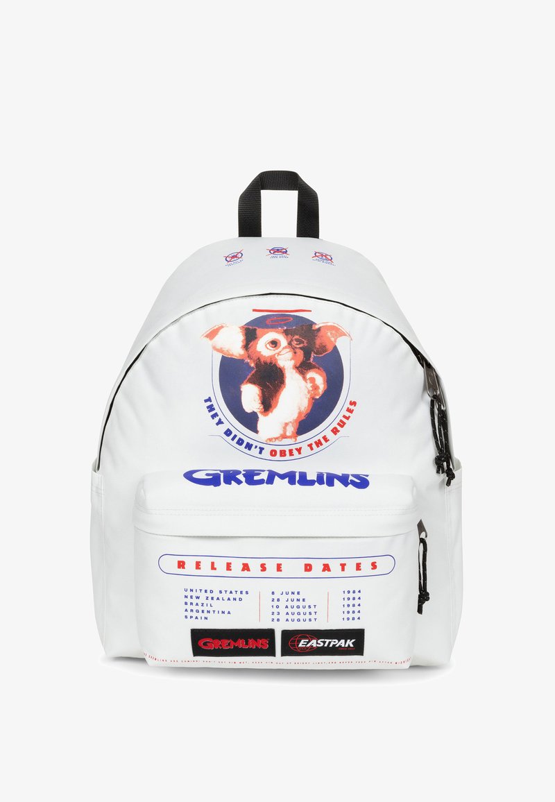 Mochila blanca con un estampado de un personaje de dibujos animados, texto azul que dice "GREMLINS" y "FECHAS DE ESTRENO", y un bolsillo delantero con cremallera.