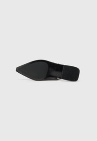 Black high-heeled shoe with a pointed toe and a textured heel. Smooth sole features a grip pattern. Simple and minimalistic design.