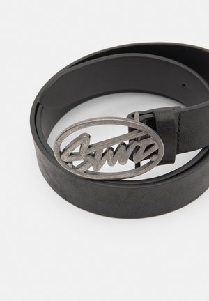 Zwarte leren riem met een ronde, zilverkleurige gesp met een cursieve logoontwerp. De riem heeft een gladde textuur en strakke lijnen.