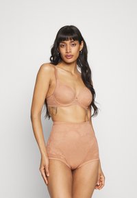 Conjunto de lencería nude que incluye un sujetador ligeramente acolchado con detalles de encaje y bragas de talle alto con patrones florales, fabricado en una tela suave.