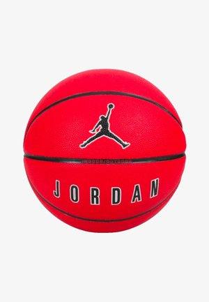 Červená basketbalová lopta vyrobená z gumy s textúrovaným povrchom. Obsahuje čierne logo Air Jordan a nápis "JORDAN" vytlačený tučnými písmenami.