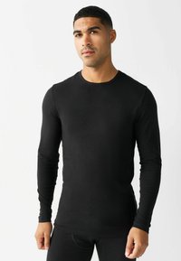 Maglietta nera a maniche lunghe realizzata in materiale liscio, con collo rotondo e design aderente, polsini a costine e silhouette senza cuciture.