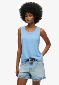 Lichtblauw mouwloos topje met een ronde halslijn, voorzien van een subtiele textuur en een klein logo. G gedragen met vervaagde denim shorts en een riem.
