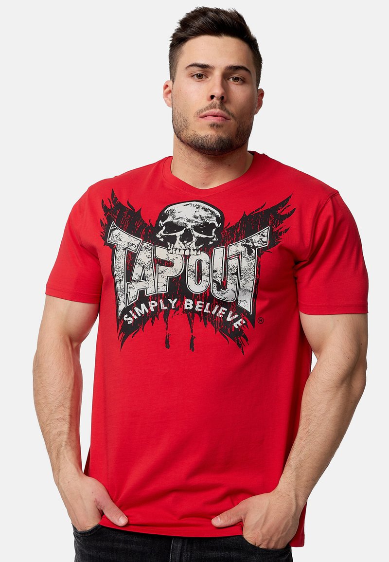 Sarkans kokvilnas T-krekls ar melnu skeleta grafiku, tekstu „TAPOUT” un traipiem. Īsās piedurknes un apaļa kakla izgriezums.