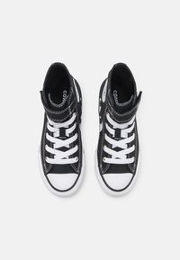Zapatillas altas de lona negra con punta de goma blanca, cordones y costuras. Presentan un cuello acolchado y un logo en el lateral.