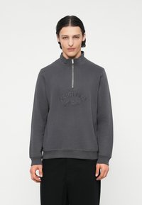 Grauer Sweatshirt mit Reißverschluss am Kragen, aus weichem Material und mit gesticktem "ORIGINALS" Logo auf der Brust sowie gerippten Bündchen und Saum.