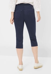 Pantaloni capri navy con una texture liscia, dotati di tasche posteriori e una vita aderente. Rifiniti con un orlo risvoltato per un aspetto curato.