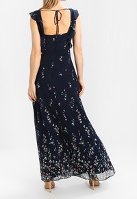 Marine maxi-jurk met bloemenprint, ruches mouwen, een strikdetail op de rug en een doorschijnende zoom. Gemaakt van lichtgewicht stof.