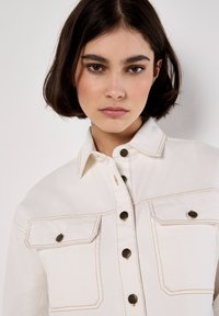 Weißes Jeansjacke aus Denim mit durchgehender Knopfleiste, zwei Brusttaschen und kontrastierenden Nähten. Verfügt über einen klassischen Kragen und metallene Beschläge.