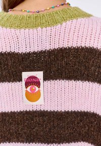 Sweter w paski z dzianiny w odcieniach brązu, różu i zieleni. Teksturowany materiał z prążkowanym kołnierzem i kolorową metką z logo z tyłu.