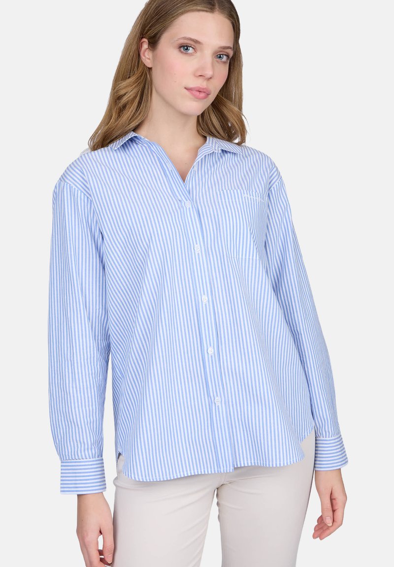 Chemise boutonnée à rayures bleues claires et blanches, avec col, manches longues, poche poitrine et coupe décontractée. Fabriquée dans un tissu doux.