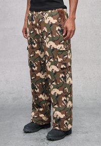Camo cargo broek in bruin, groen en beige. Voorzien van een elastische tailleband, zijzakken en zachte textuurdetails.