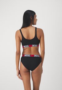 Svart bomull bralette med tynne stropper, med en rød og hvit "DIESEL" logo-bånd; kombinert med matchende høylivde bikini truser.