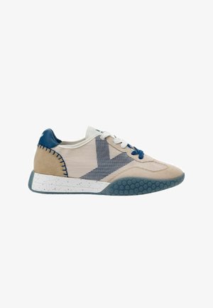 Sneaker beige e bianca con dettagli blu, pannelli in mesh, lacci bianchi e blu e suola blu testurizzata con intersuola maculata.