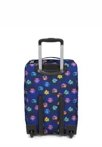 Maleta con ruedas sobre un fondo azul marino, decorada con un patrón floral de coloridas violetas, y un mango retráctil con detalles en negro.