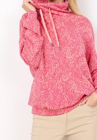 Pink hoodie with a floral and zebra print pattern, funnel neck, and drawstring accents. Cozy fabric and relaxed fit.