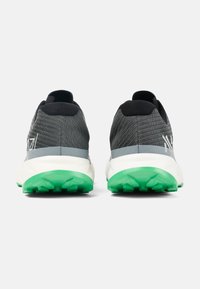 Grijze sportieve schoenen met een gestructureerde bovenkant, zwarte accenten en een groene rubberen zool. Heeft een gestroomlijnd ontwerp met reflecterende details.