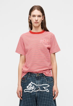 Donna che indossa una maglietta a righe rosse e bianche con la scritta "ICECREAM" e pantaloni blu a motivo pied de poule con stampa di un cane cartone animato bianco.