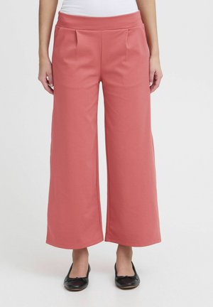 Weite Hosen aus weichigem Korallstoff, mit hohem Bund, vorderen Falten und glatter Textur, kombiniert mit schwarzen Ballerinas.