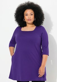Paarse tuniek met een vierkante hals, driekwartmouwen en zakken; gemaakt van zachte stof met een losse pasvorm. Eenvoudig ontwerp met een gladde textuur.