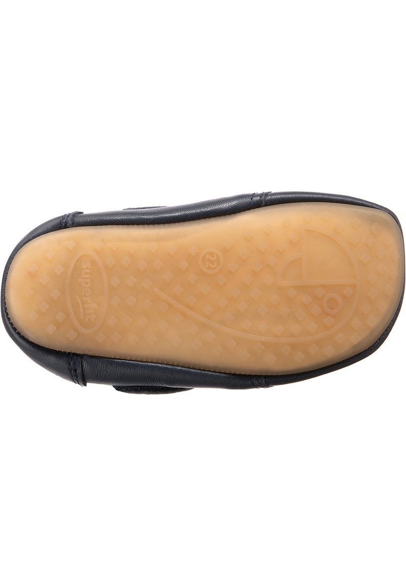 Schwarze Ledersohle mit einer strukturierten beigen Gummisohle, die ein erhöhtes Muster und subtile Logodetails im Fersenbereich aufweist.