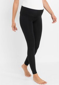 Leggings de maternité noirs avec une large taille douce et une coupe ajustée. Fabriqués en tissu lisse et extensible, idéaux pour le confort.