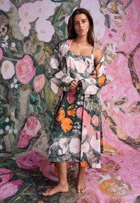 Jurk met bloemenpatroon van zachte stof, met levendige oranje en roze bloemen op een donker groene achtergrond. Losse pasvorm met bijpassende sjaal.