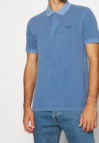 Polo bleu en coton, doté d'un col, de manches courtes et d'un discret logo Levi's brodé sur la poitrine.