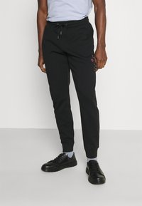 Schwarze Jogginghosen mit einem Kordelzugbund, geripptem Saum und mehrfarbigen Logoakzenten an der Seite. Hergestellt aus einem weichen Stoff.