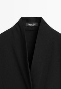 Blazer nero con colletto a revers e tessuto liscio, con un'etichetta all'interno che mostra "Massimo Dutti" e "Made in Morocco".