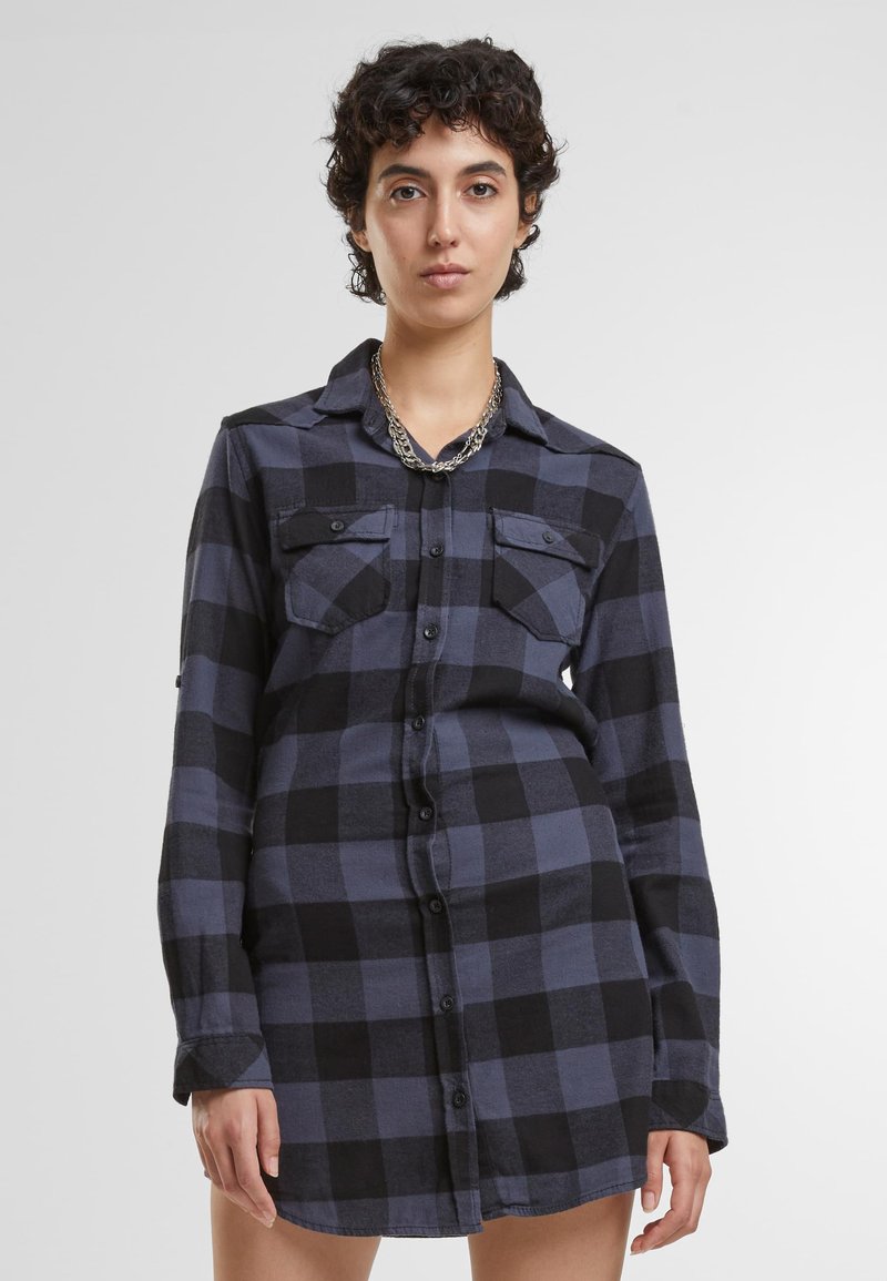 Abito camicia a maniche lunghe in una fantasia a quadri blu scuro e nero, con chiusura a bottoni, due tasche sul petto e una vestibilità morbida.